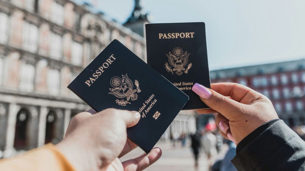 2 people holding passports in front of old european building