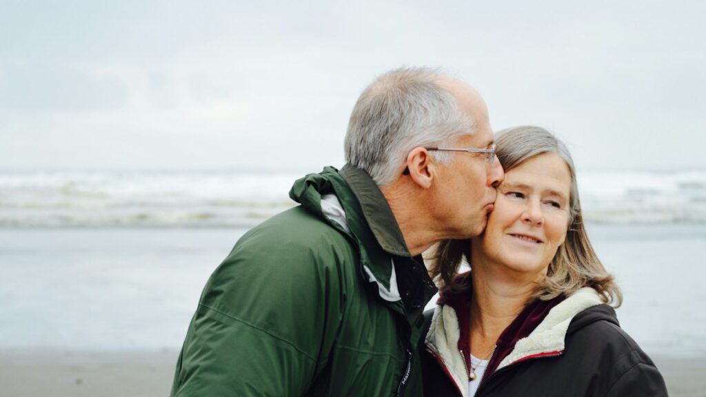 elderly couple kissing on beach