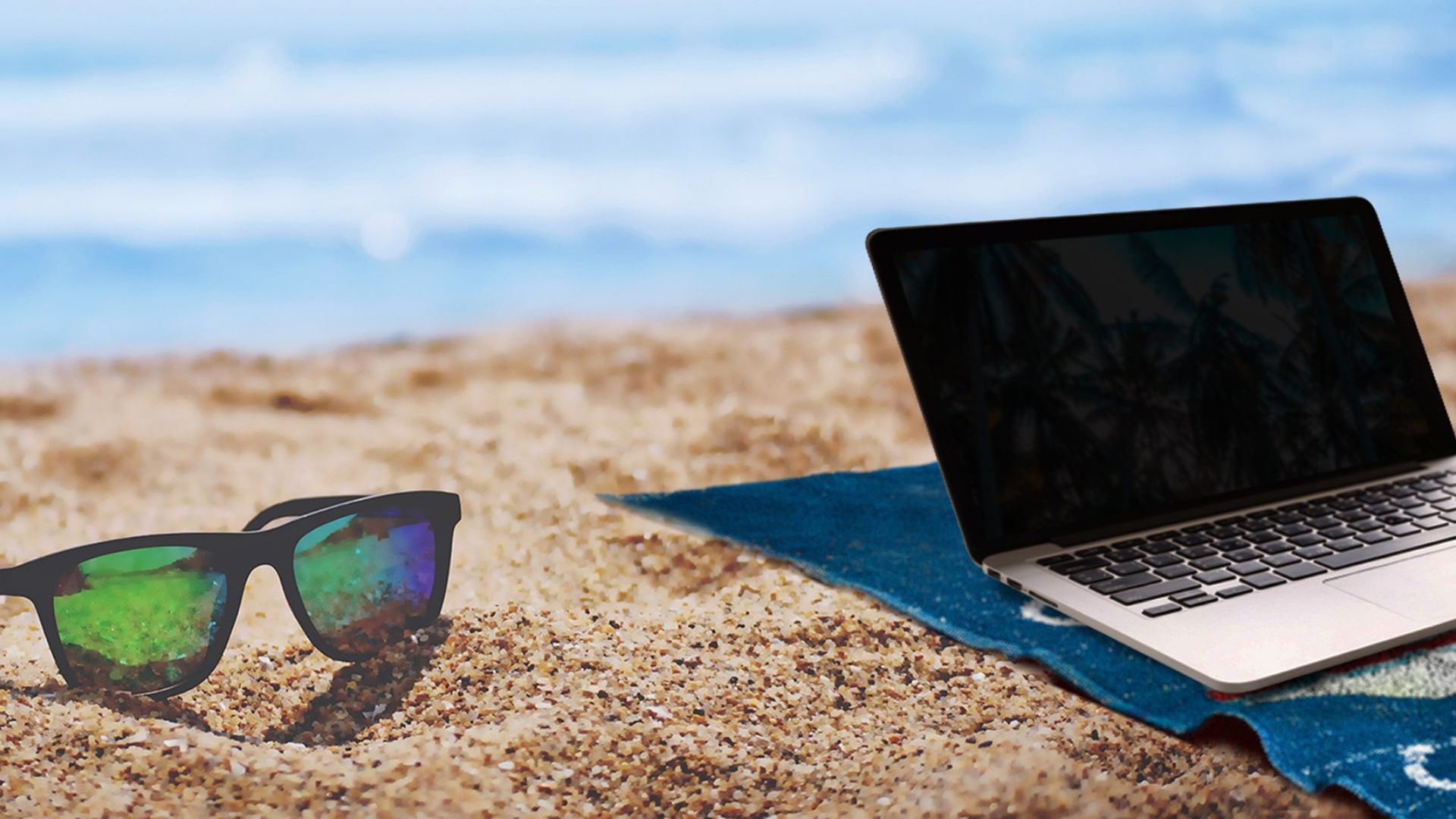 laptop and sunglasses on beach